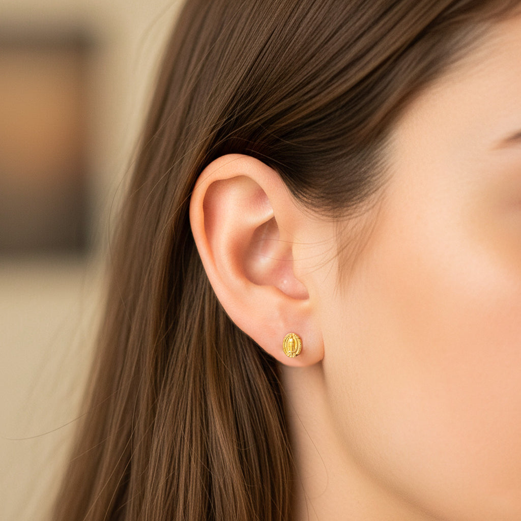 Oreja de modelo usando un topito de la Virgen de Guadalupe en oro amarillo de 18 quilates de Joyería Caracas. 