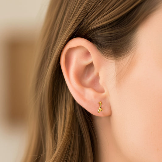 Oreja de modelo usando un topito en forma de jirafa en oro amarillo de 18 quilates de Joyería Caracas. 