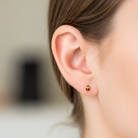 Oreja de modelo usando un topito en forma de lady bug en oro amarillo de 18 quilates de Joyería Caracas. 