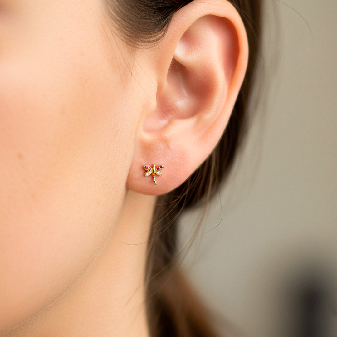 Oreja de modelo usando un topito en forma de libélula en oro amarillo de 18 quilates con cristales de Joyería Caracas. 