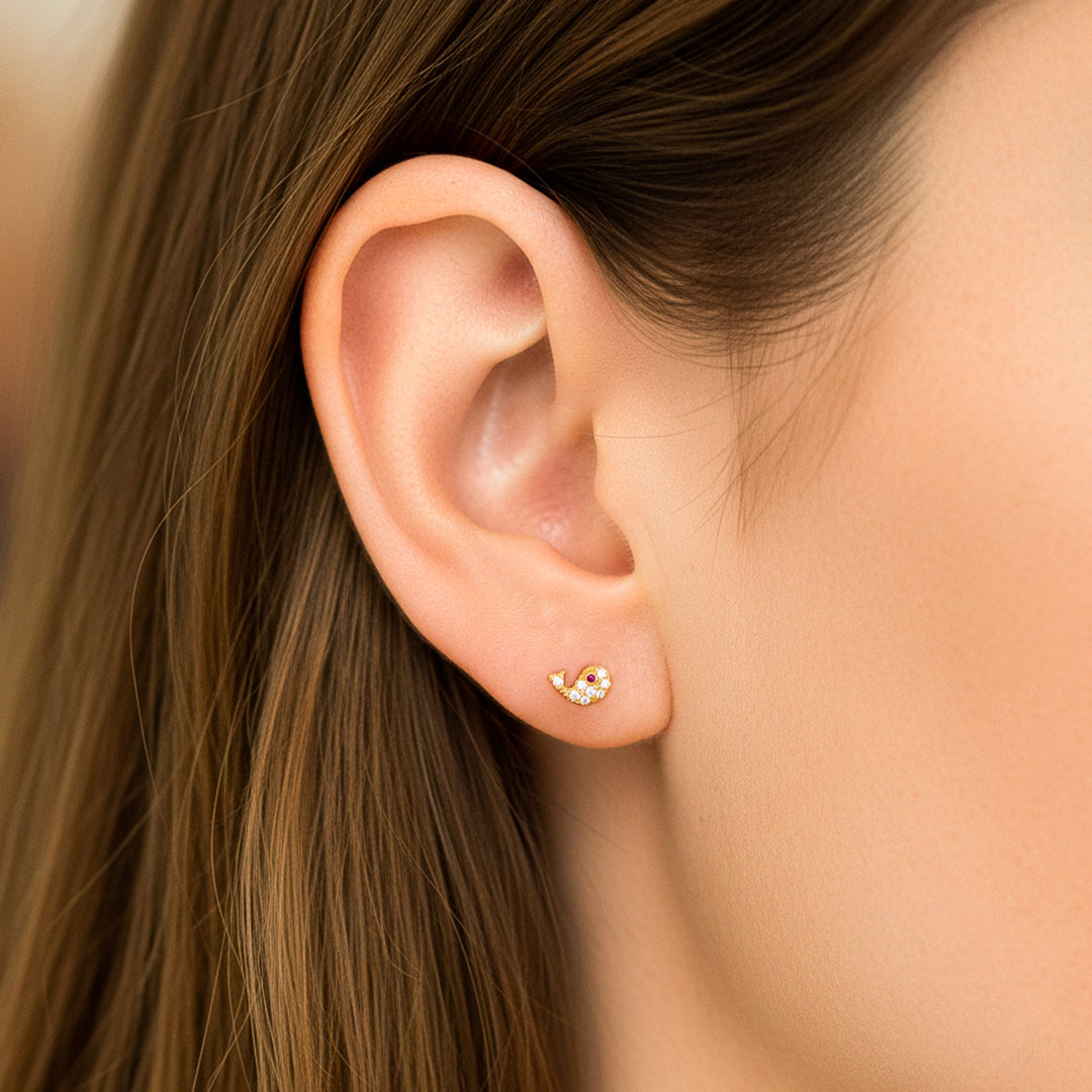 Oreja de modelo usando un topito en forma de ballena en oro amarillo de 18 quilates con cristales de Joyería Caracas. 