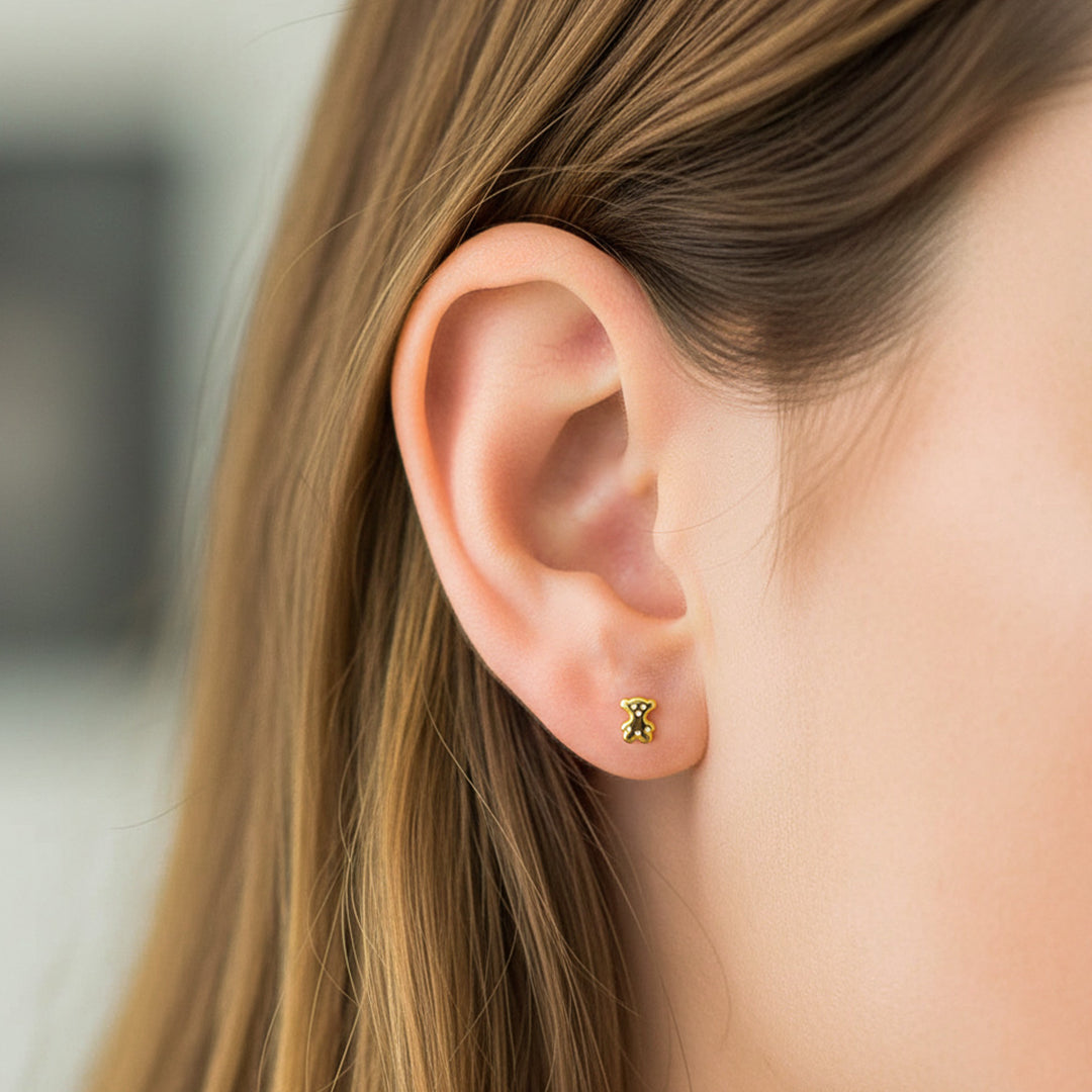 Oreja de modelo usando un topito en forma de oso en oro amarillo de 18 quilates de Joyería Caracas. 