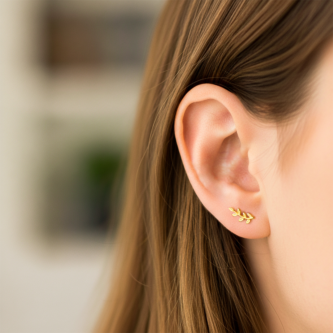 Oreja de modelo usando un topito en forma de rama en oro amarillo de 18 quilates de Joyería Caracas. 