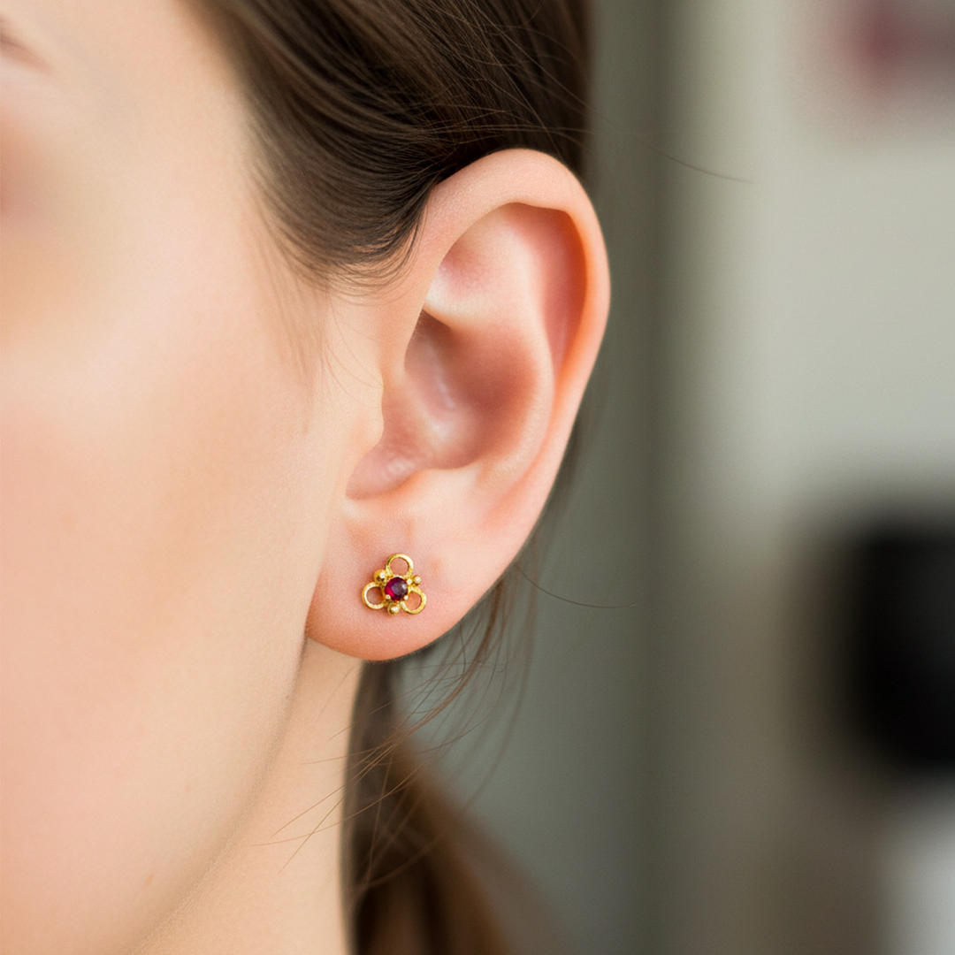Oreja de modelo usando un topito en forma de flor de 3 pétalos en oro amarillo de 18 quilates con cristal de Joyería Caracas. 