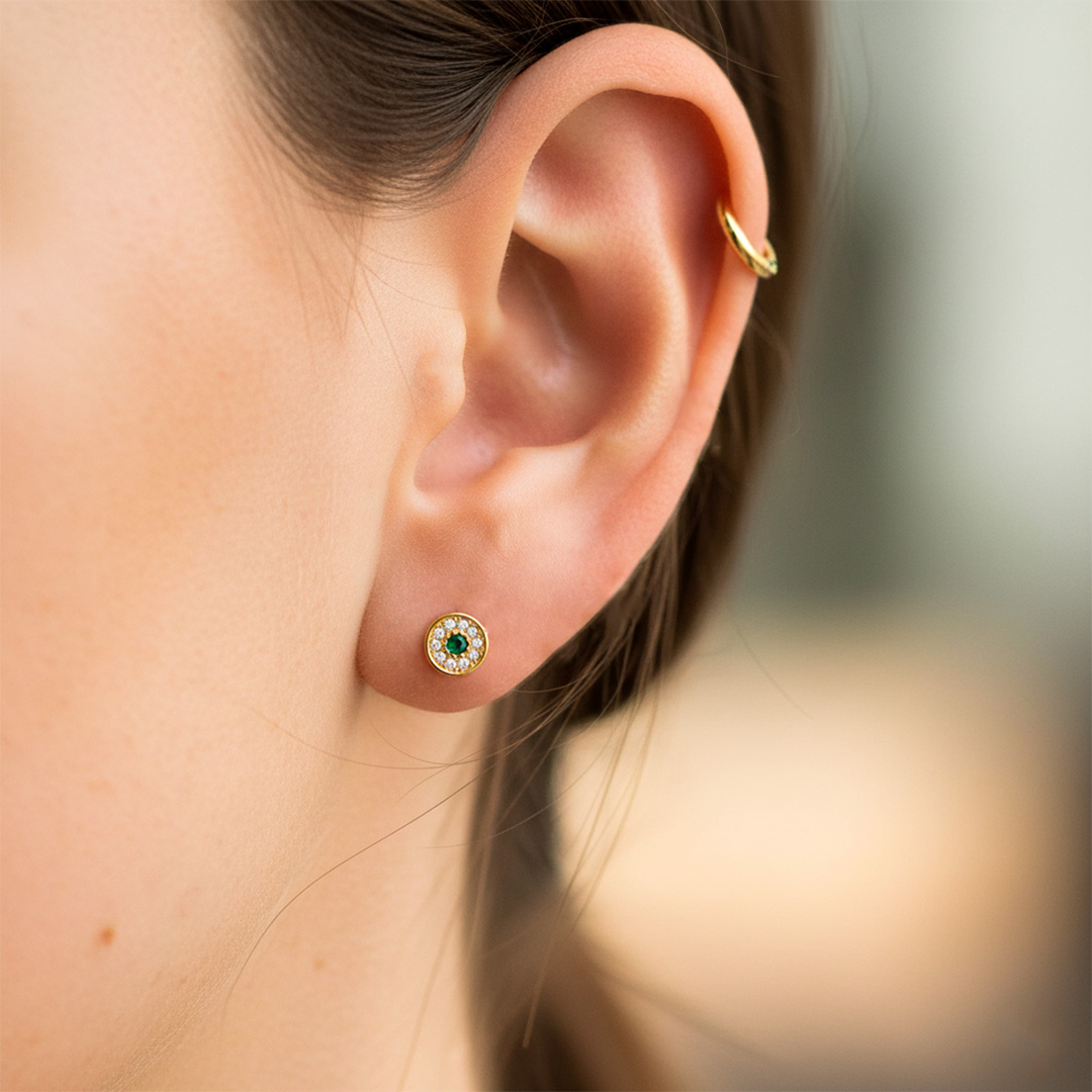 Oreja de modelo usando un topito en forma de rueda en oro amarillo de 18 quilates con cristales de Joyería Caracas. 