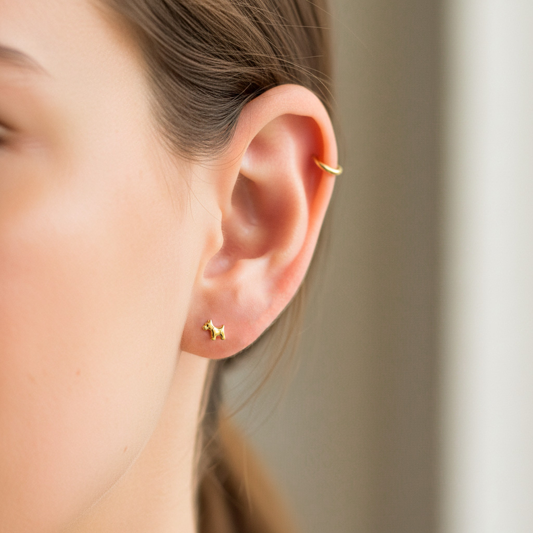 Oreja de modelo usando un topito en forma de schnauzer en oro amarillo de 18 quilates de Joyería Caracas. 