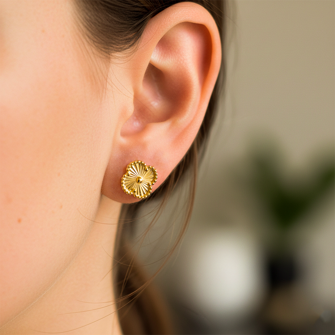 Oreja de modelo usando un topito en forma de trébol en oro amarillo de 18 quilates de Joyería Caracas. 