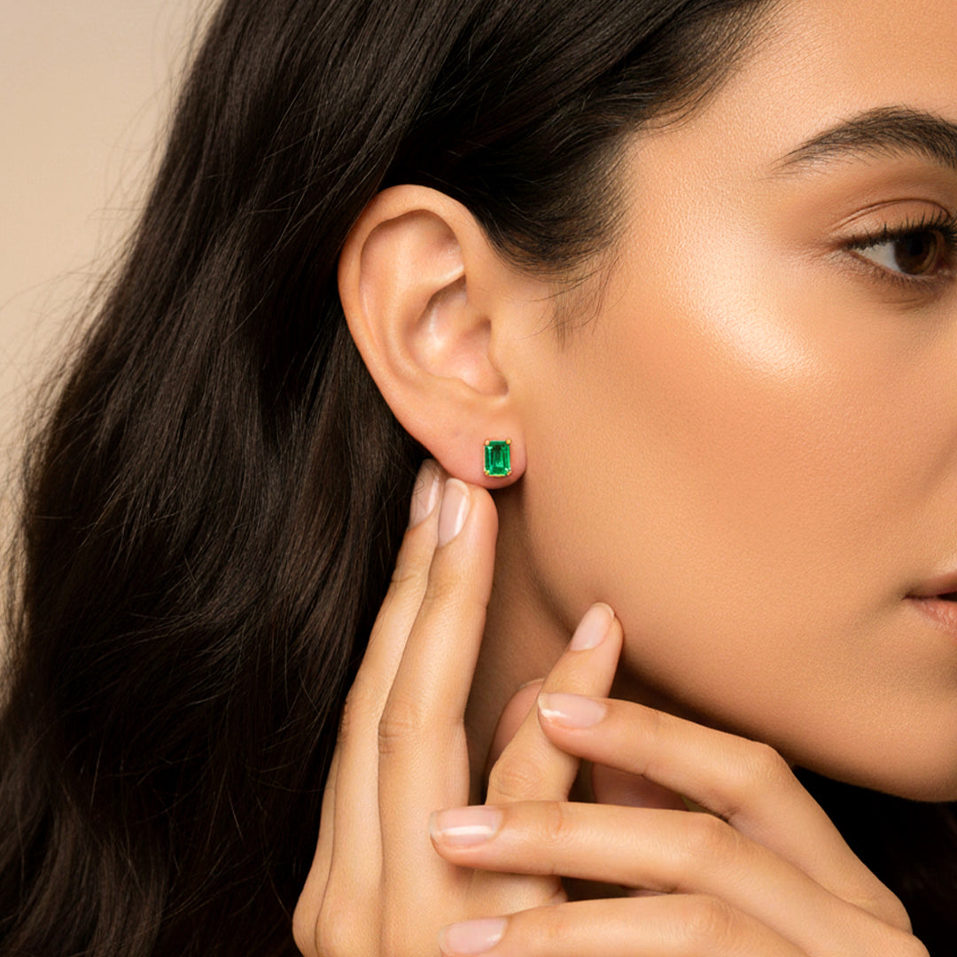 Oreja de modelo usando un topito en oro amarillo de 18 quilates con Esmeralda en corte Baguette de Joyería Caracas. 