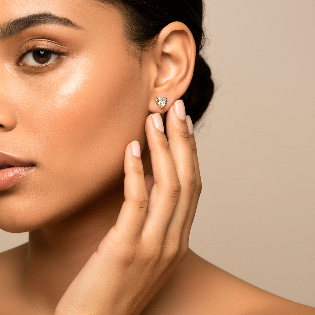 Oreja de modelo usando un topito en forma de corazón en oro amarillo de 18 quilates con cristal en forma de corazón de Joyería Caracas. 