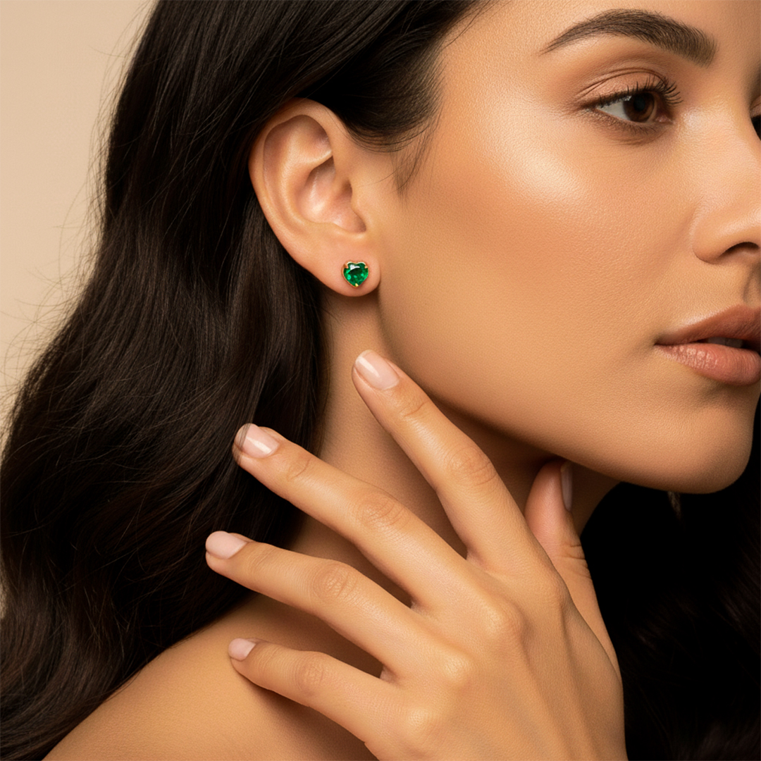 Oreja de modelo usando un topito en forma de corazón en oro amarillo de 18 quilates con Esmeralda en forma de corazón de Joyería Caracas. 