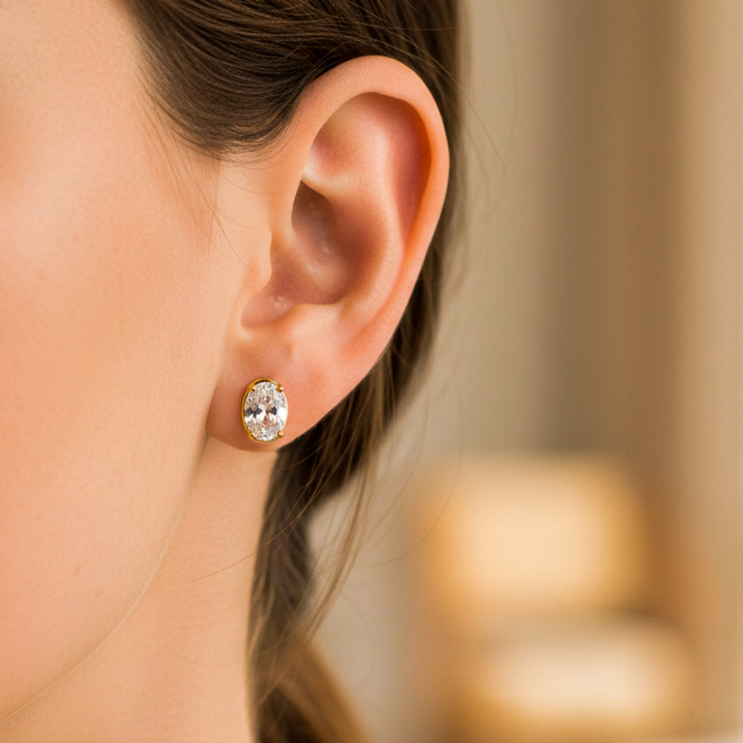 Oreja de modelo usando un topito ovalado en oro amarillo de 18 quilates con cristal ovalado de color blanco de Joyería Caracas. 