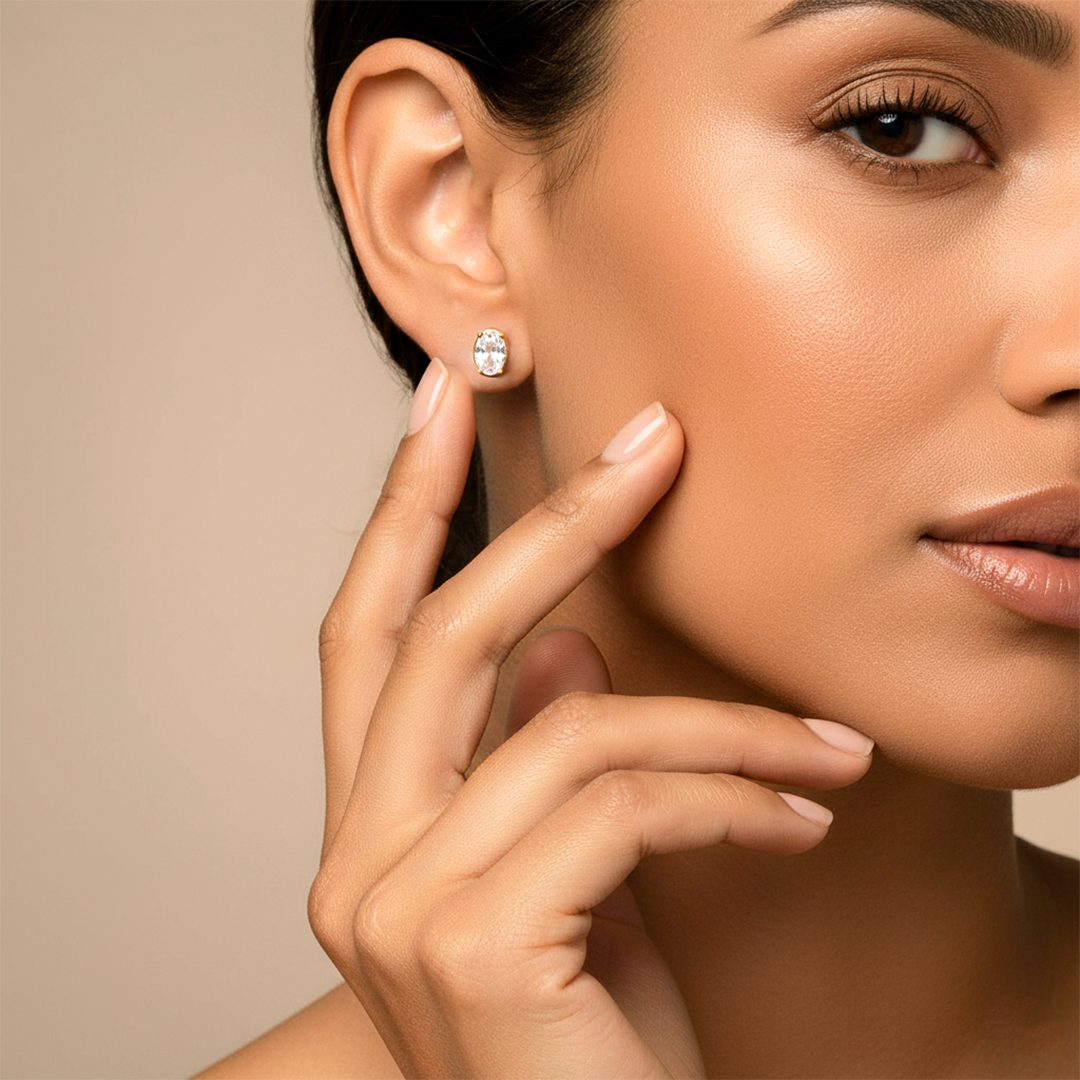 Oreja de modelo usando un topito ovalado en oro amarillo de 18 quilates con cristal ovalado de color blanco de Joyería Caracas. 