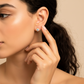 Oreja de modelo usando un topito redondo en oro amarillo de 18 quilates con cristal de color blanco de Joyería Caracas. 