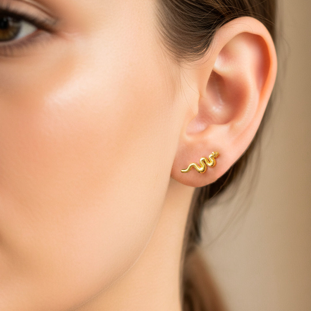 Oreja de modelo usando un topito en forma de serpiente en oro amarillo de 18 quilates de Joyería Caracas.