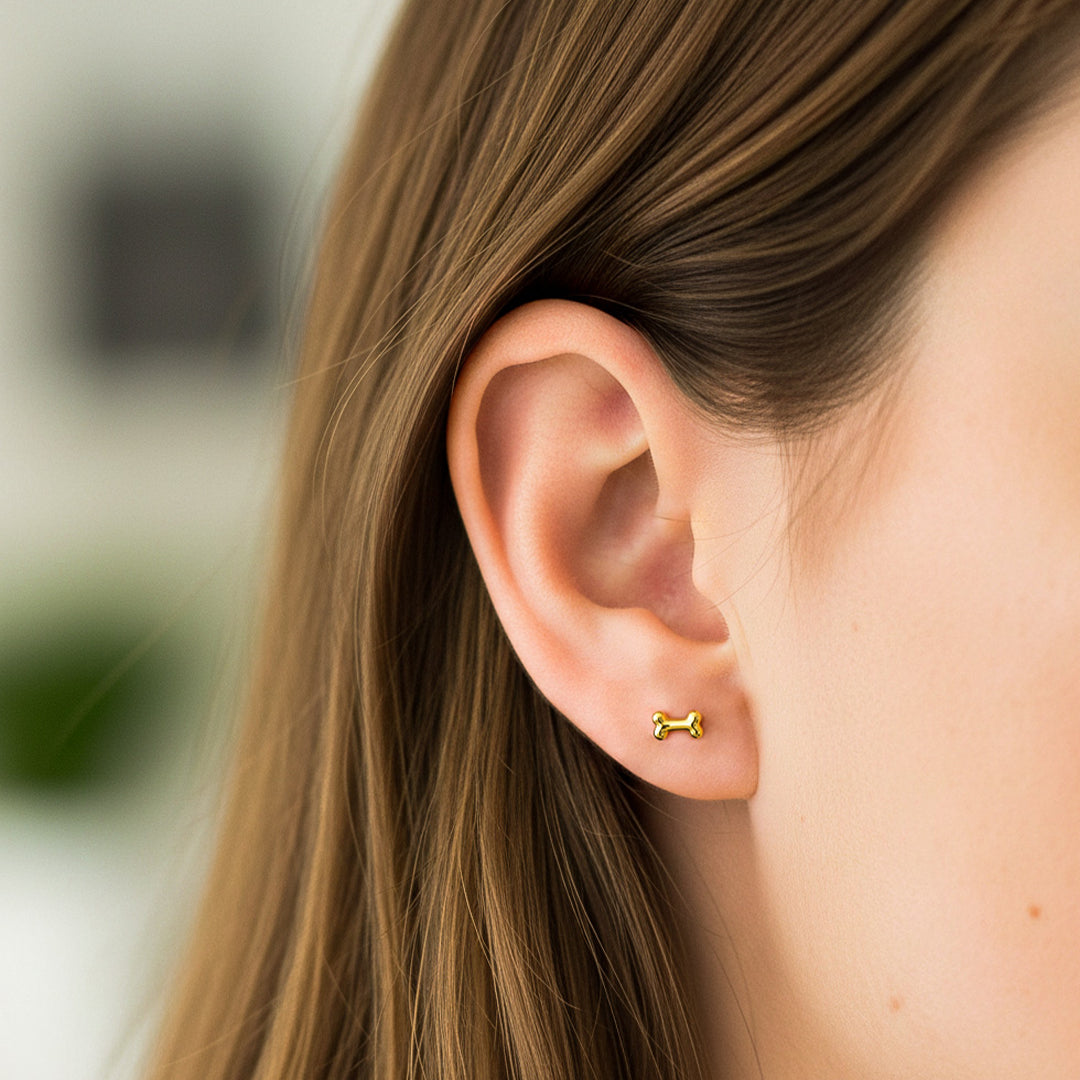 Oreja de modelo usando un topito en forma de hueso en oro amarillo de 18 quilates de Joyería Caracas. 